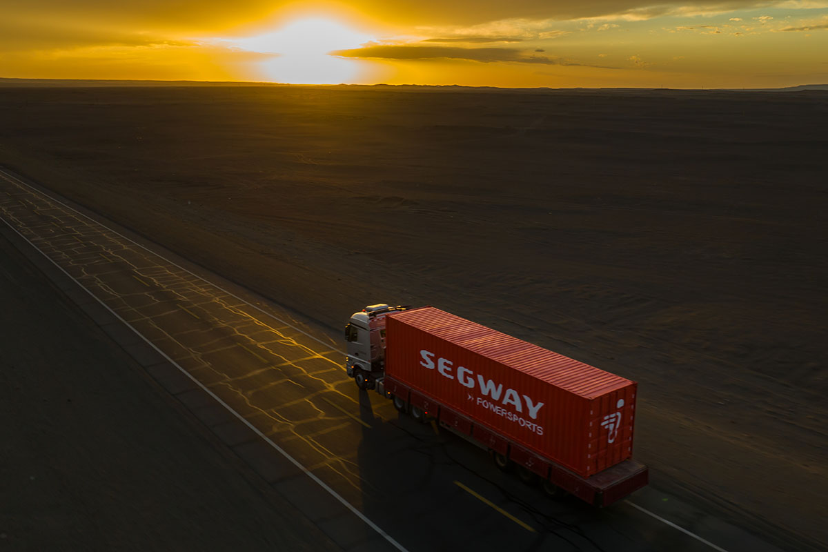 Segway Powersports-lastbil kör längs en öde landsväg i solnedgången, symbol för trygg leverans.